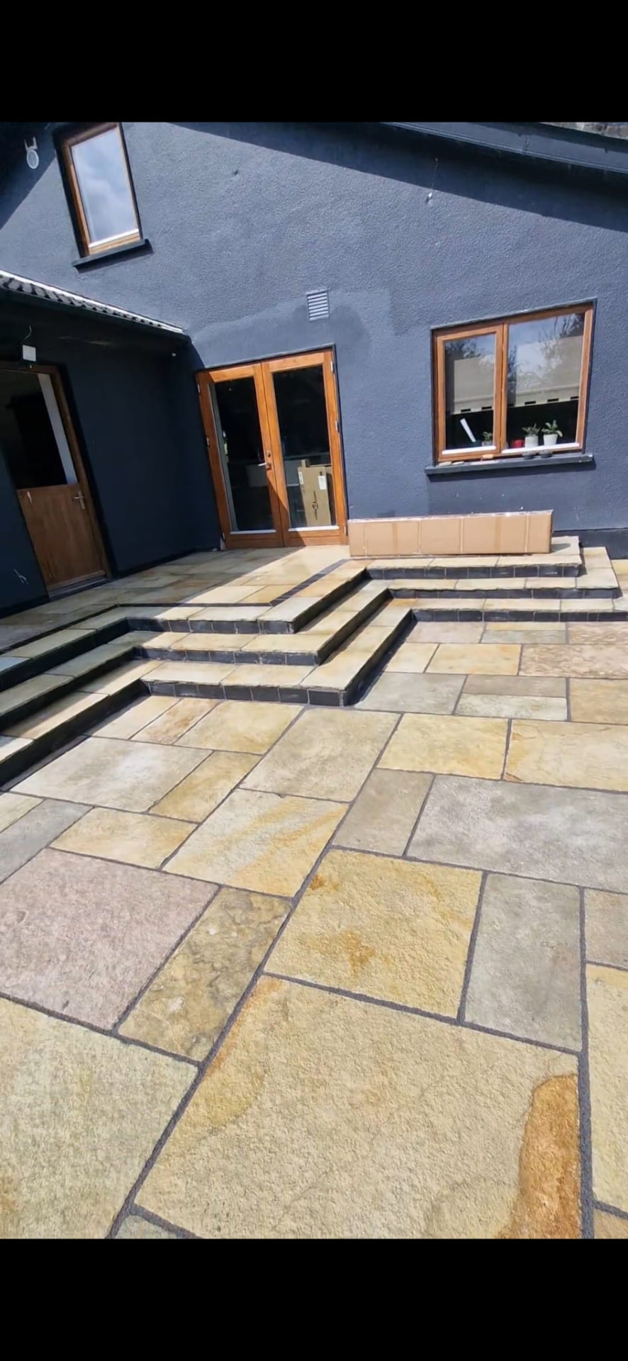 Natural stone paving project in Laois with steps outside a dark house | Farrell Exteriors